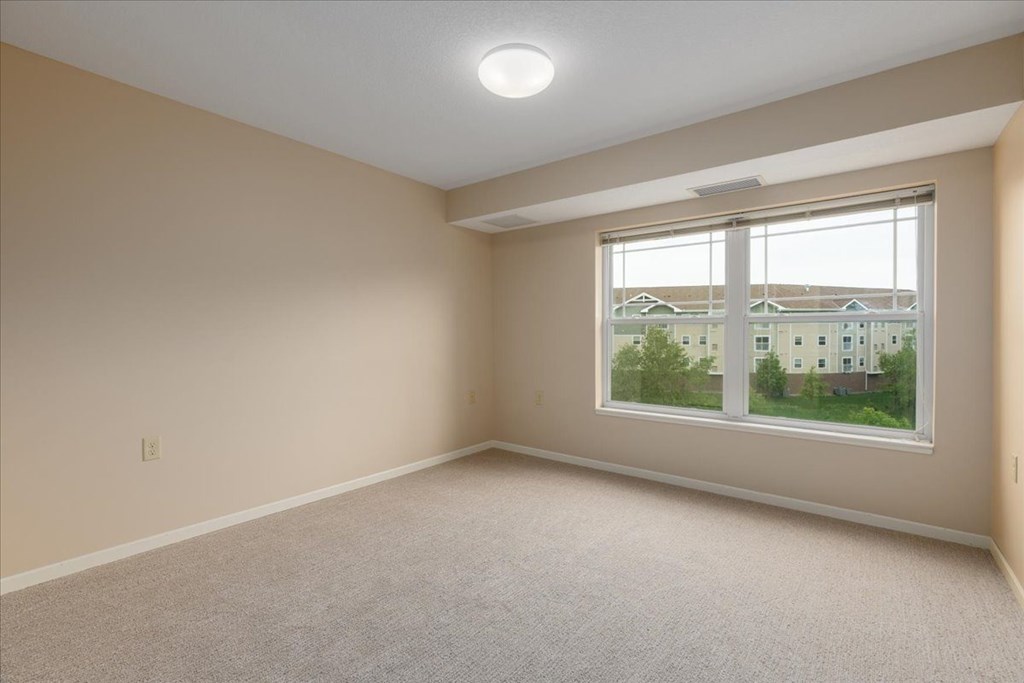 A room with a large window and carpeted floor.
