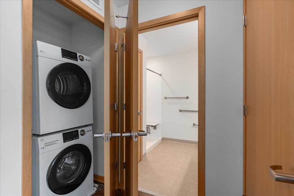 A washing machine and dryer are stacked on top of each other in a small room.