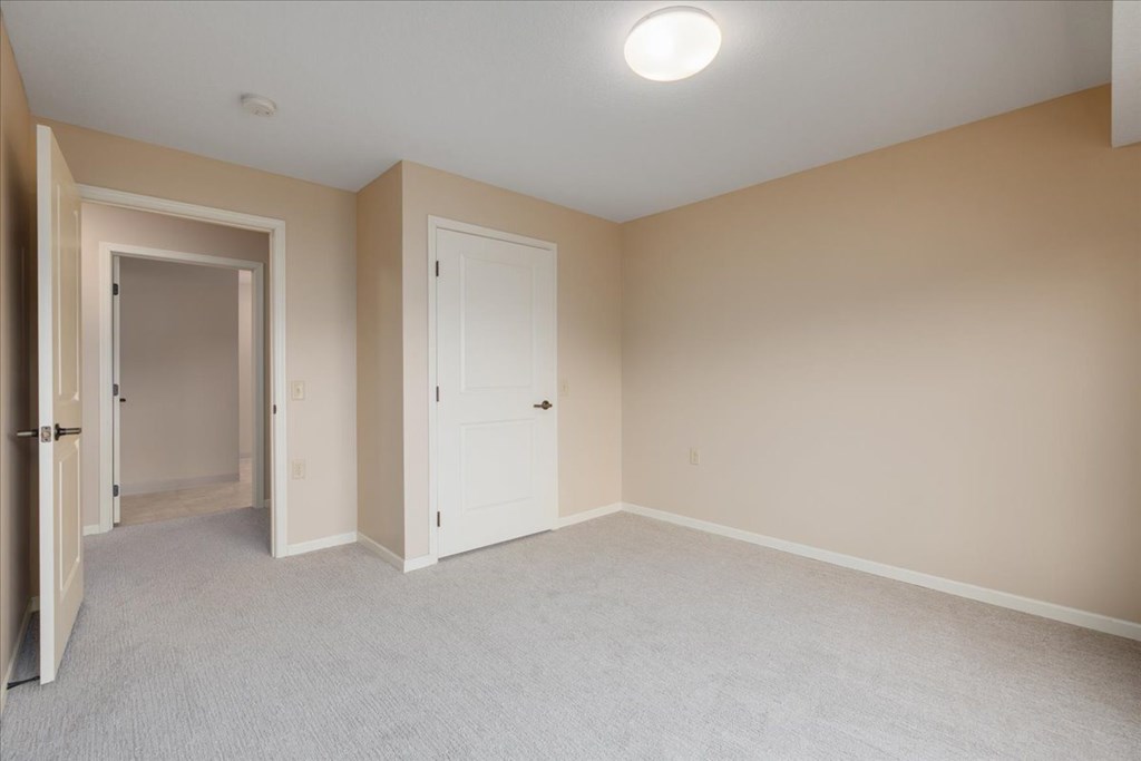 A room with a carpeted floor and two doors.