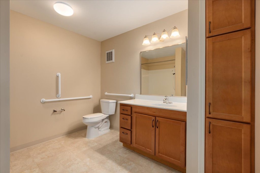 A bathroom with a toilet, sink, and a mirror.