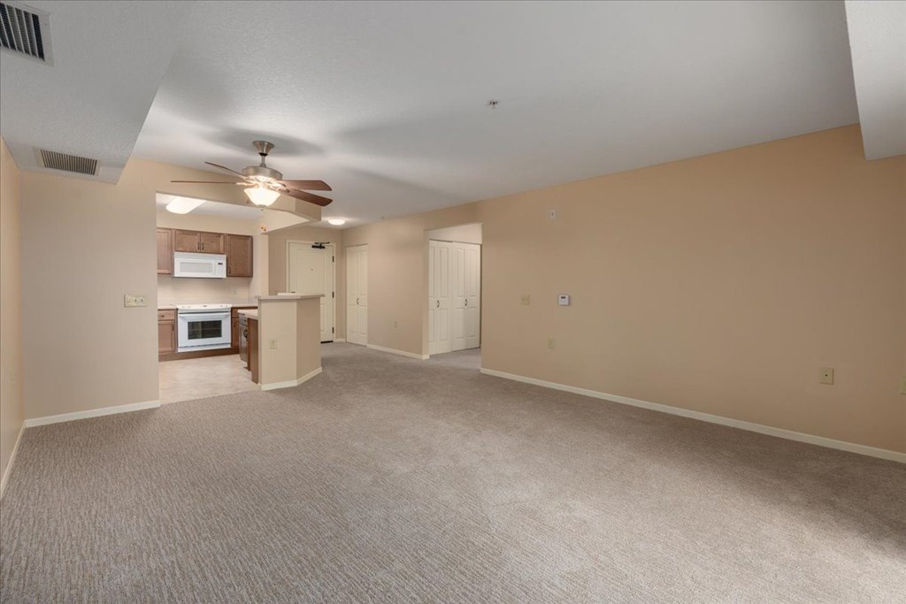 A spacious room with a ceiling fan and carpeted floor.