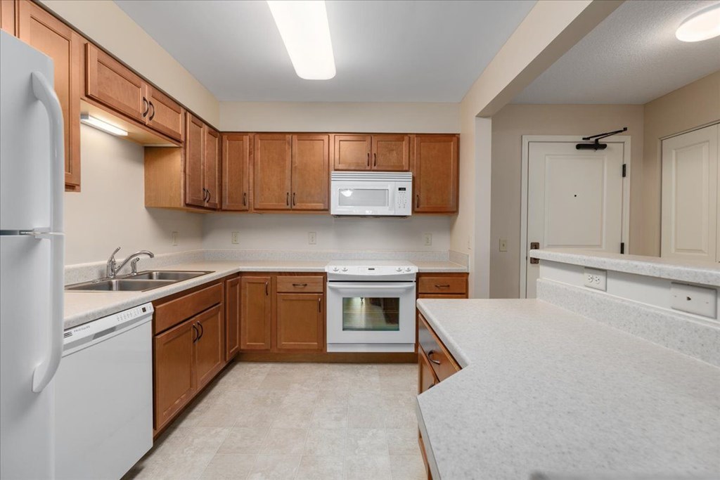 A kitchen with white appliances and wooden cabinets.