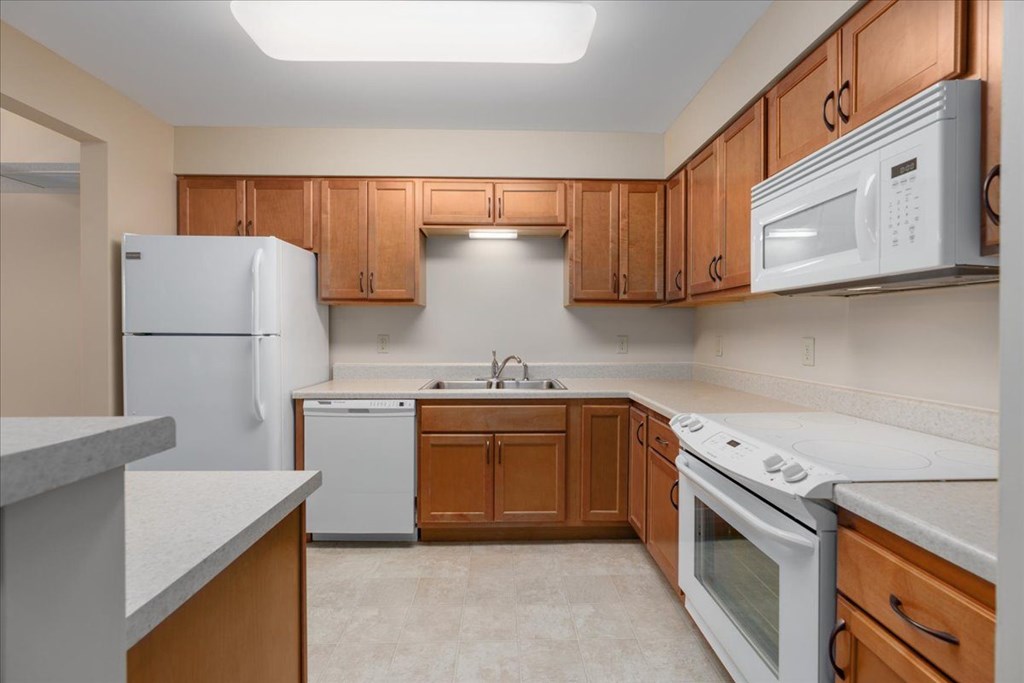 A kitchen with white appliances and wooden cabinets.