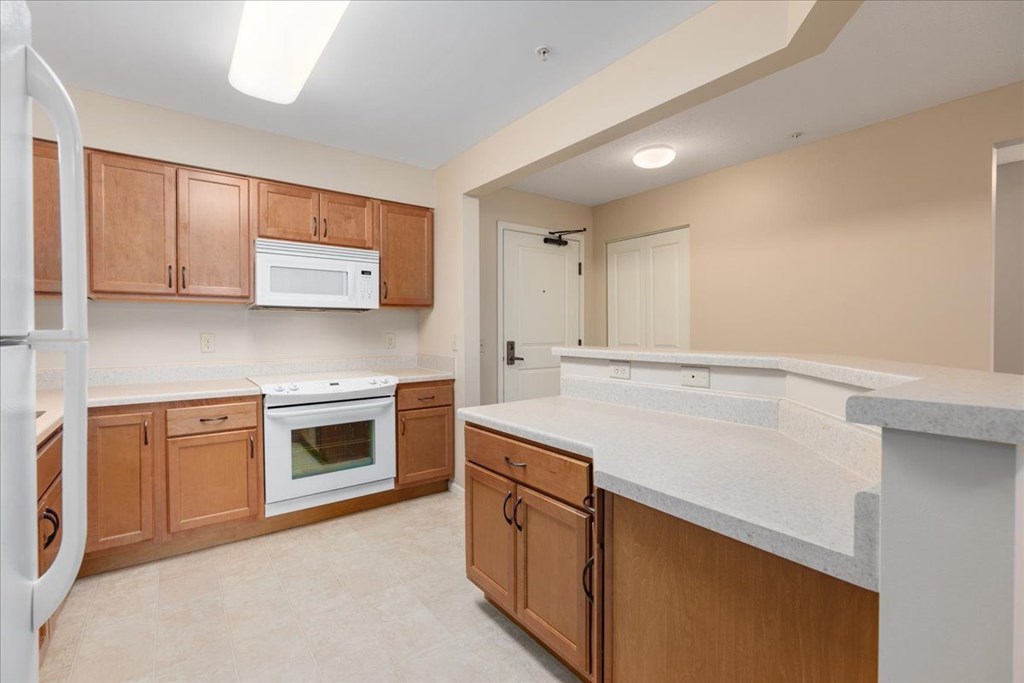 A kitchen with brown cabinets and white appliances.