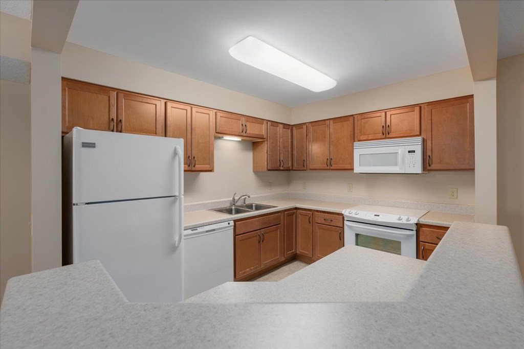 A kitchen with white appliances and wooden cabinets.