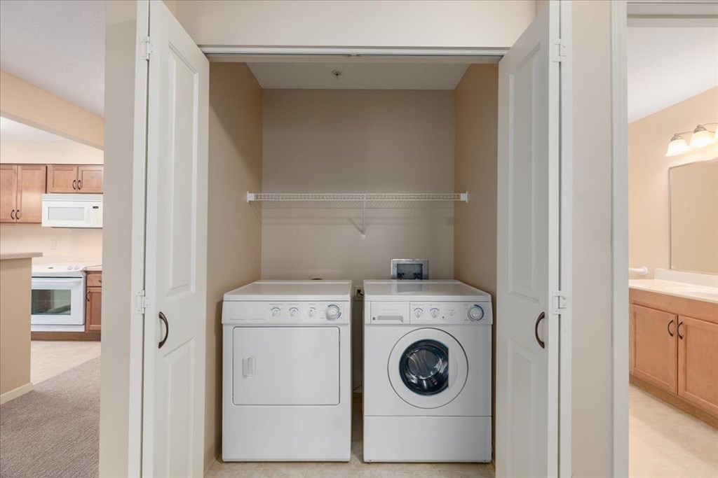 A white dryer and washer are in a small laundry room.
