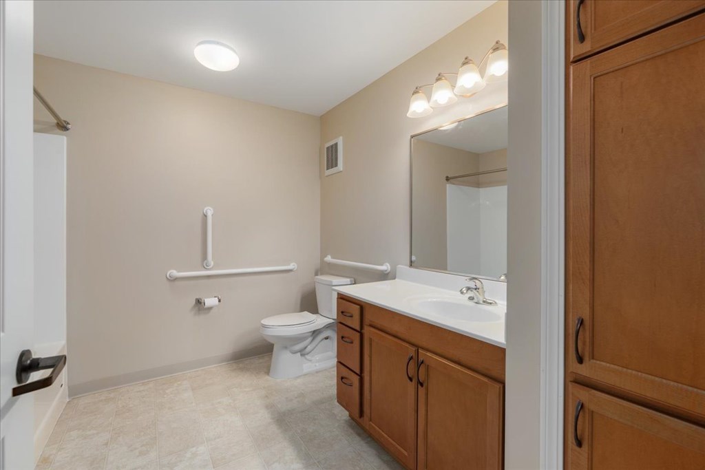 A bathroom with a toilet, sink, and mirror.