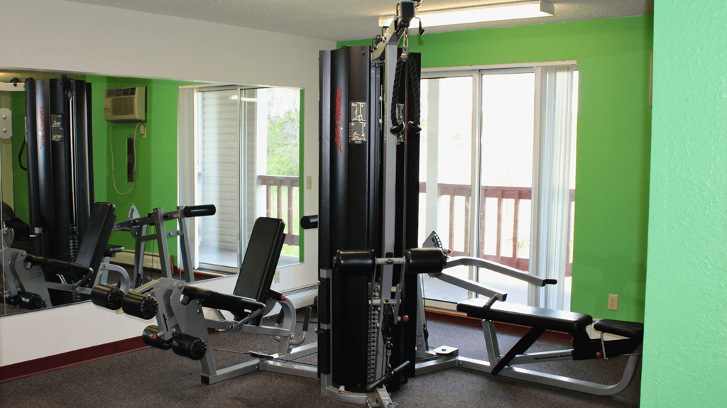 a home gym with exercise equipment in a room with green walls