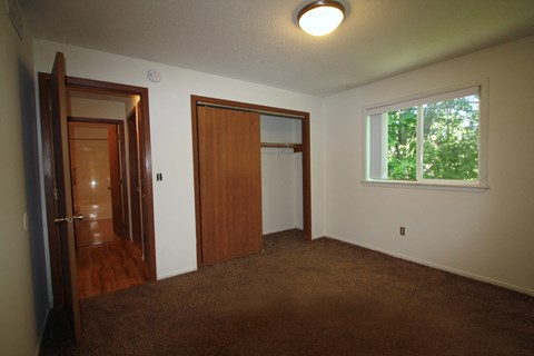 an empty living room with a door to a closet and a window