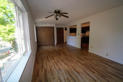 an empty living room with wooden floors and a ceiling fan