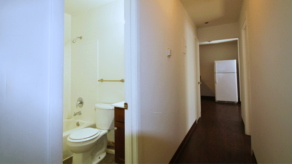 a bathroom with a toilet and a sink and a refrigerator