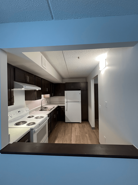 A kitchen with a white stove top oven and a white refrigerator.