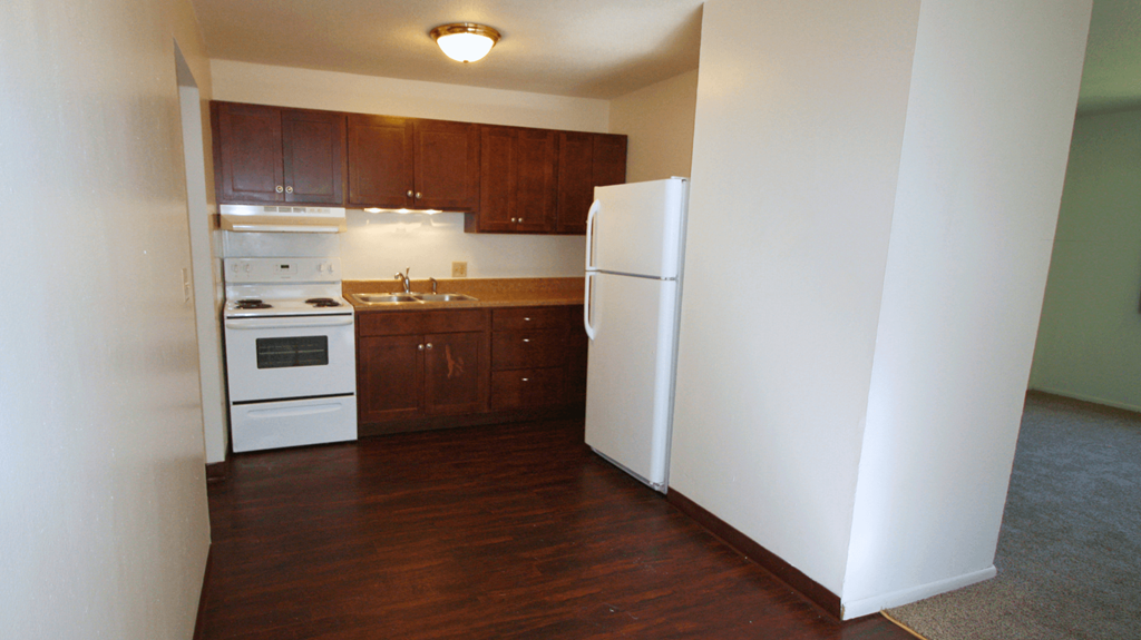an empty kitchen with white appliances and wooden cabinets