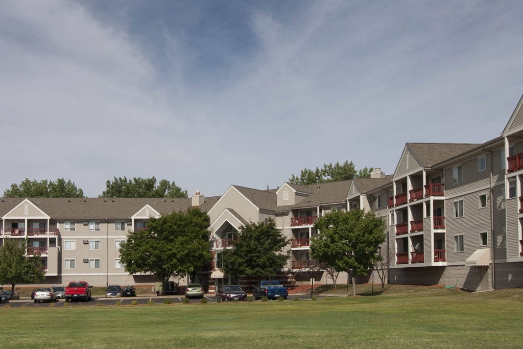 a row of apartment buildings on the side of a grass field