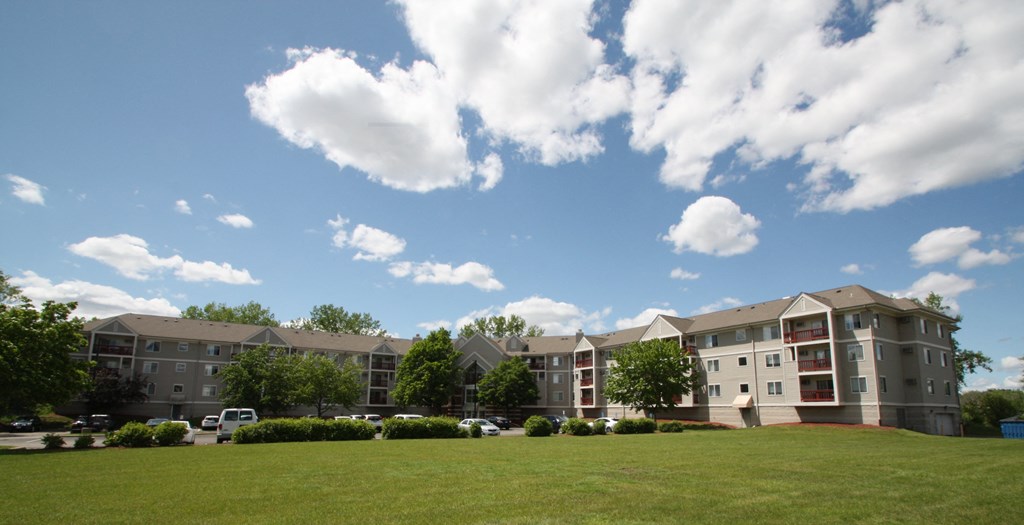 an exterior view of an apartment building on a green lawn