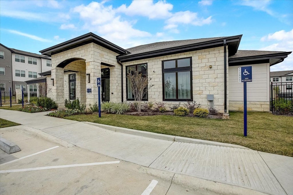 the front of a brick building with a handicapped sign on the sidewalk
