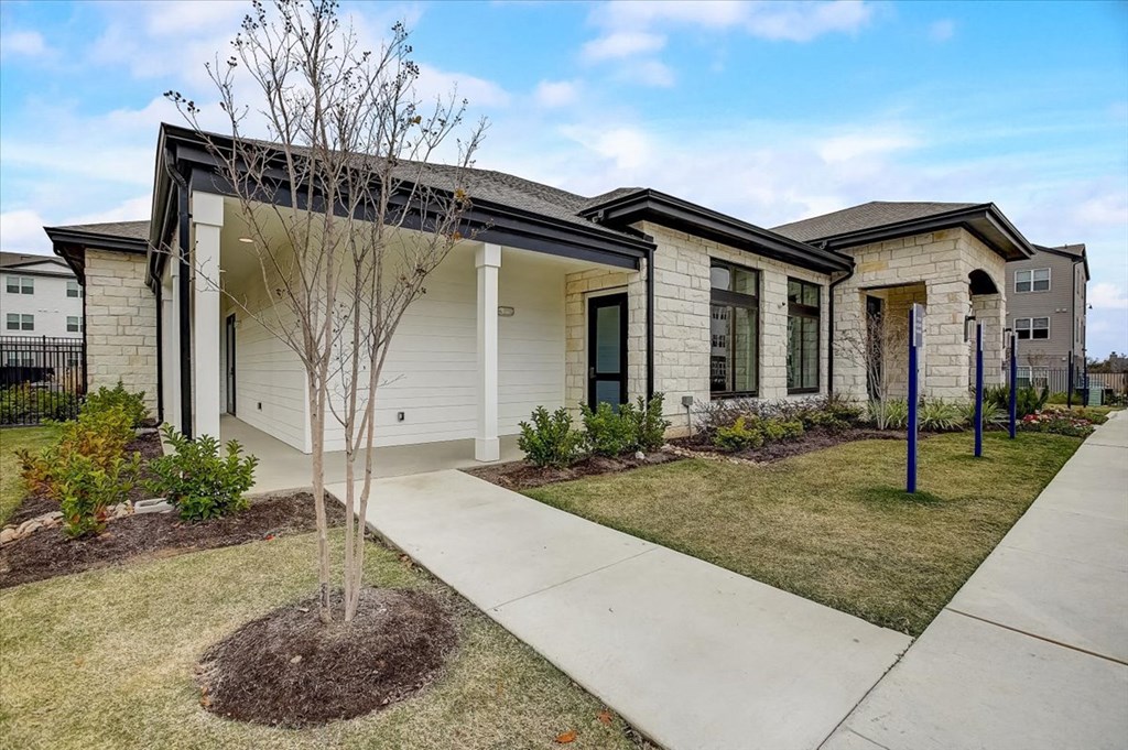 a house with a sidewalk and a tree in front of it