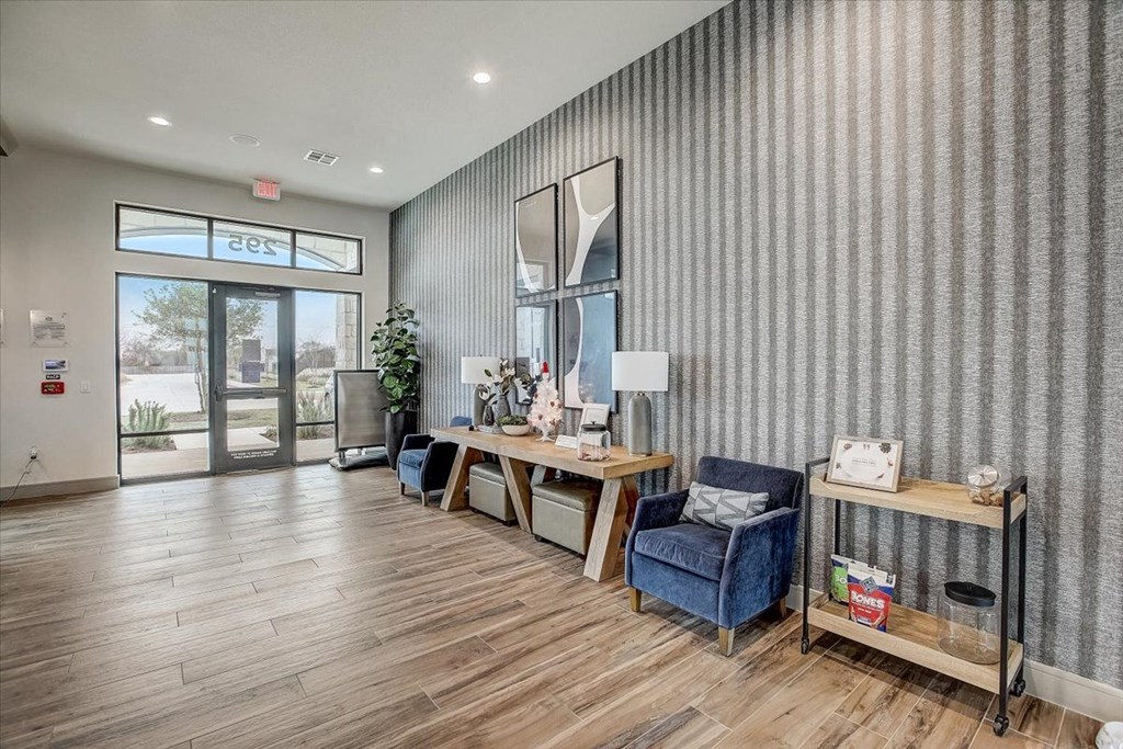 a lobby with chairs and a table and a glass door