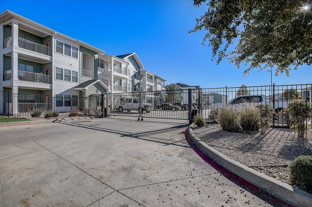 a fenced in parking lot with an apartment building in the background