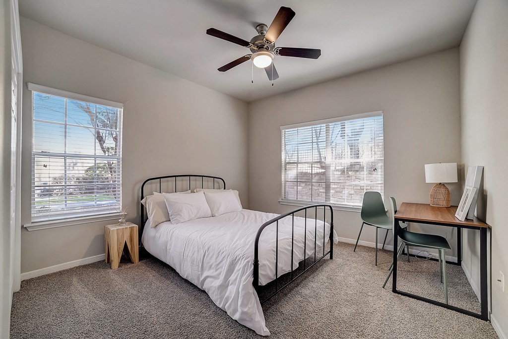 an empty bedroom with a bed and a ceiling fan