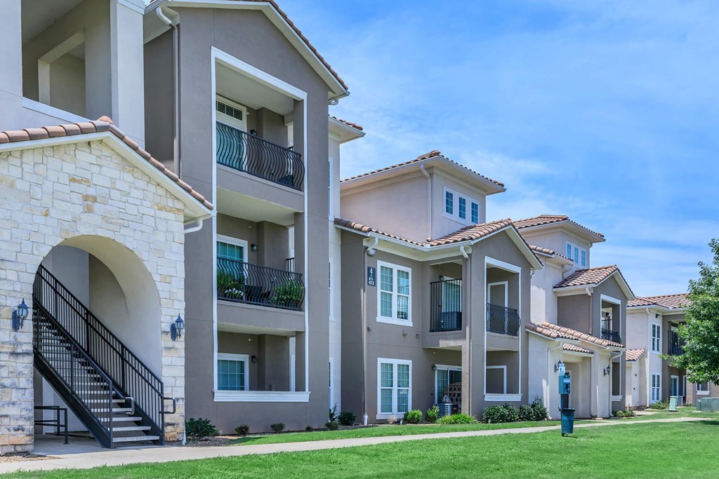 A row of apartment buildings with balconies and a clear blue sky.