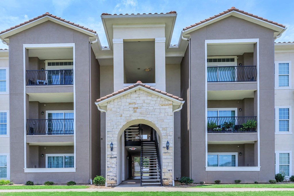 A large building with a stone archway entrance and balconies on the second floor.
