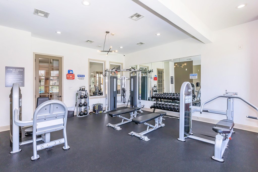 A gym with a variety of equipment including a leg press machine, a squat rack, and a bench press.