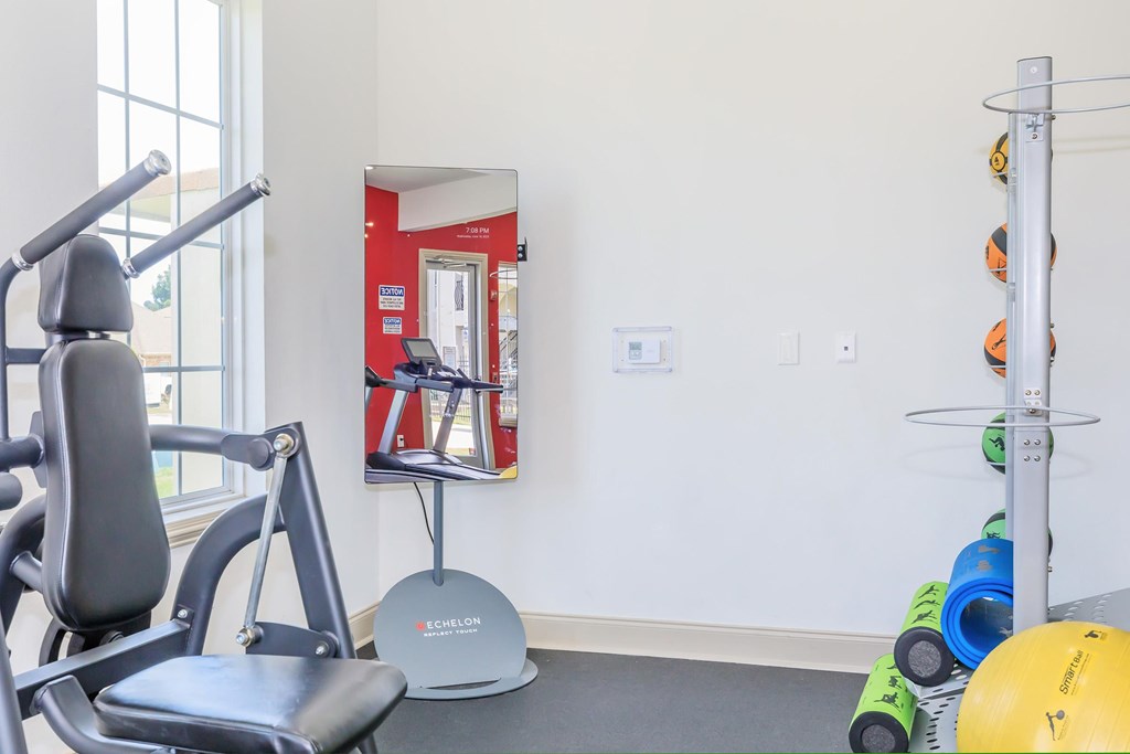 A gym room with a rowing machine and a ball.