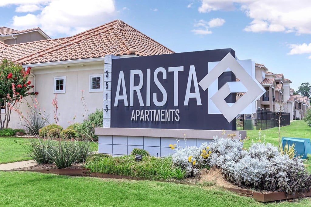 A sign for Arista Apartments is in front of a building.