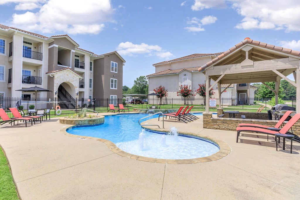 A large outdoor swimming pool with a fountain in the middle of it.