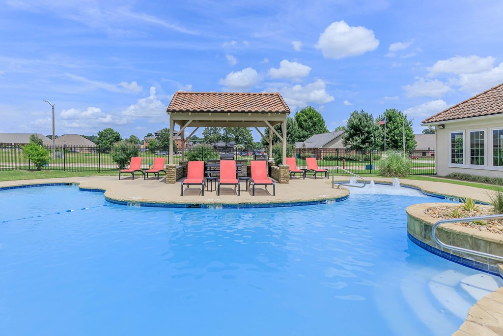 A pool with a gazebo and chairs around it.