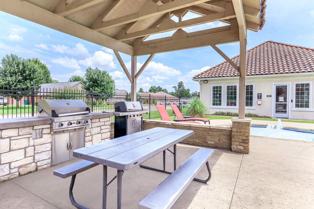A picnic table is under a canopy next to a pool.