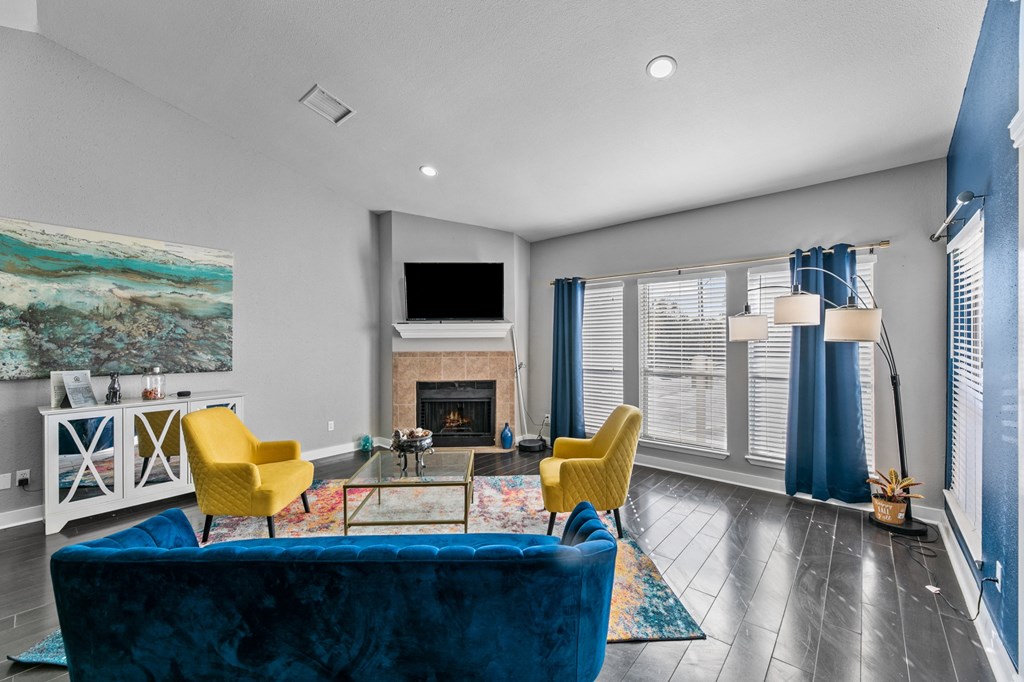 a living room with a blue couch and yellow chairs and a fireplace