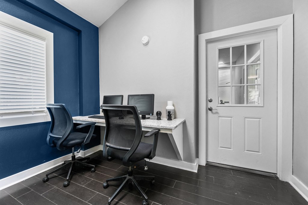 a home office with desks and chairs and a door