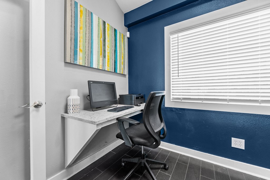 an office with a desk with a computer and a chair