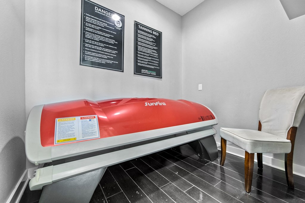 a red exam table in a room with a chair and a bench