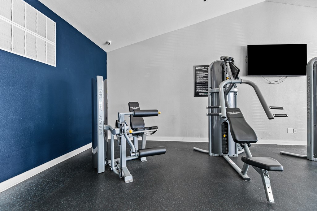 a gym with cardio equipment and a tv on the wall