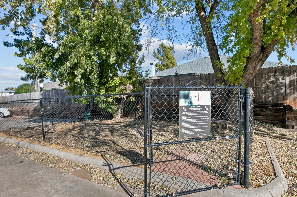 a fence with a sign on it in front of a dog park