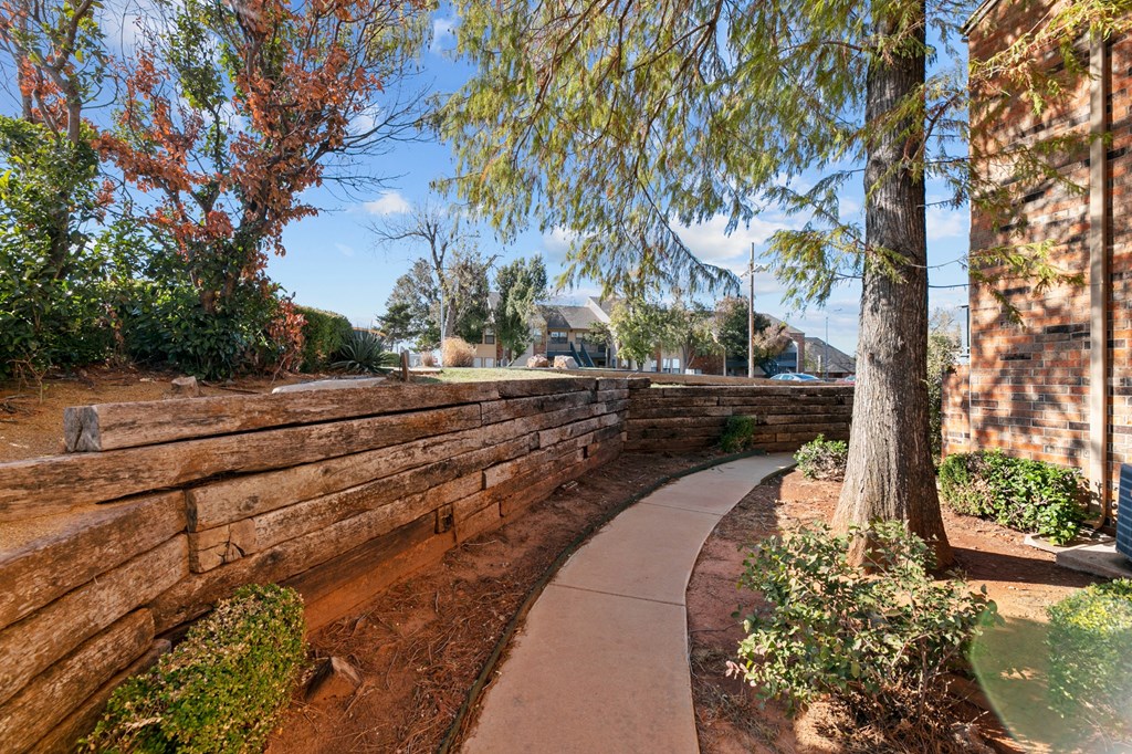a walkway next to a retaining wall with trees