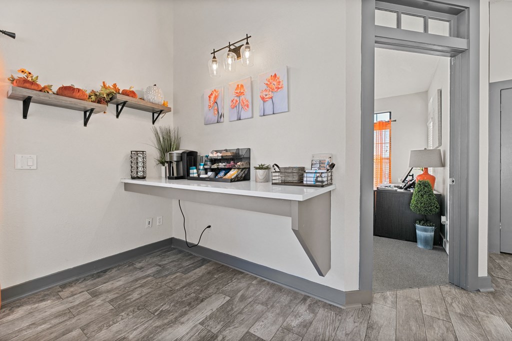 the living room of a house with a white wall and a table with a shelf