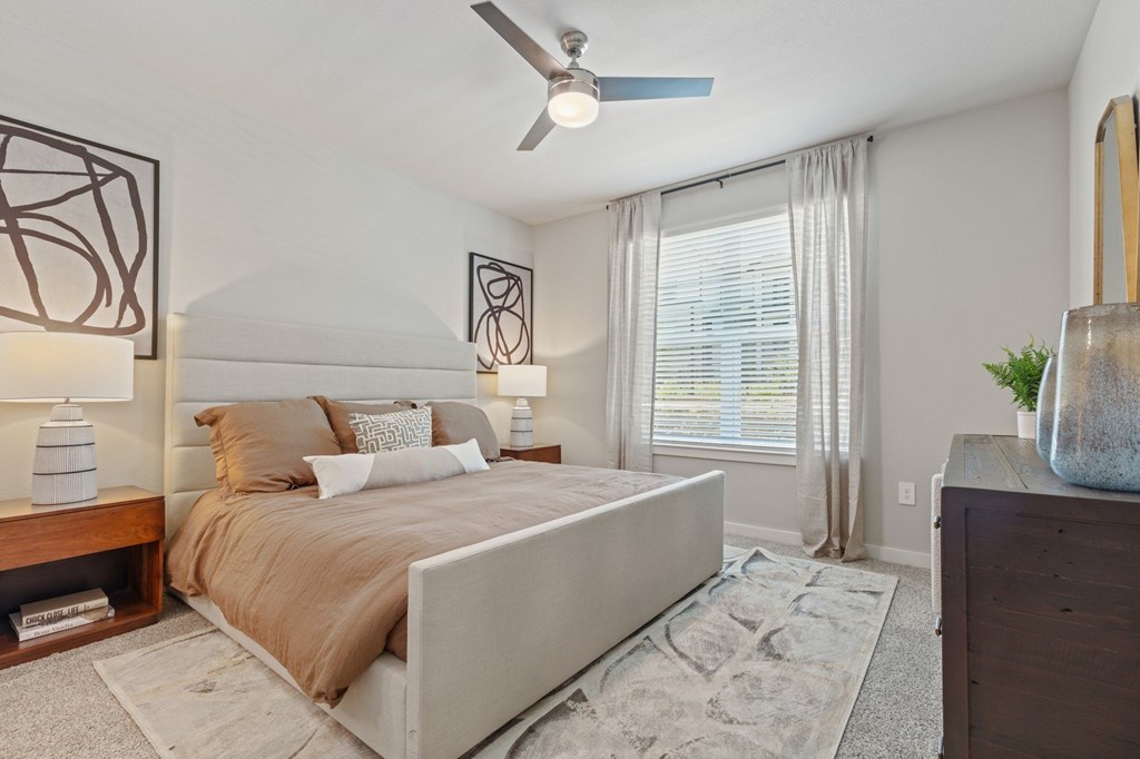 A bedroom with a large bed, a ceiling fan, and a rug on the floor.