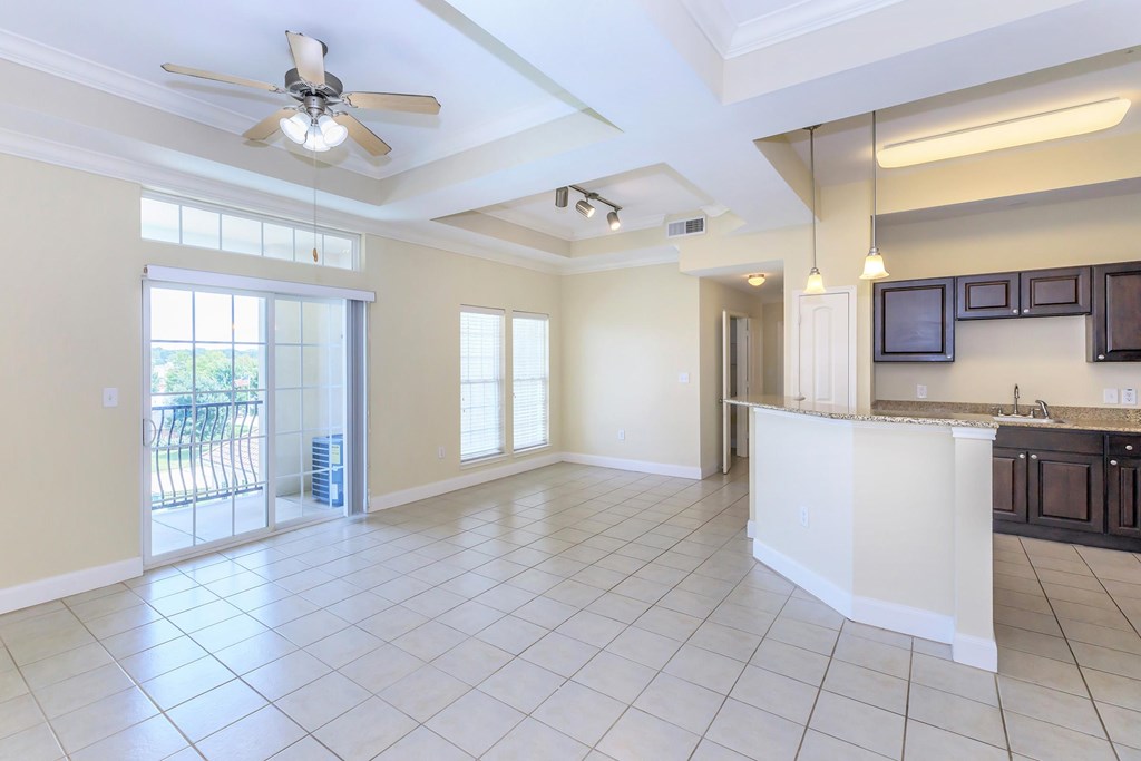 A spacious kitchen and living room with a ceiling fan and sliding glass doors.