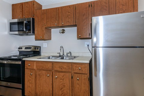 A kitchen with a stainless steel refrigerator, microwave, oven, and sink.
