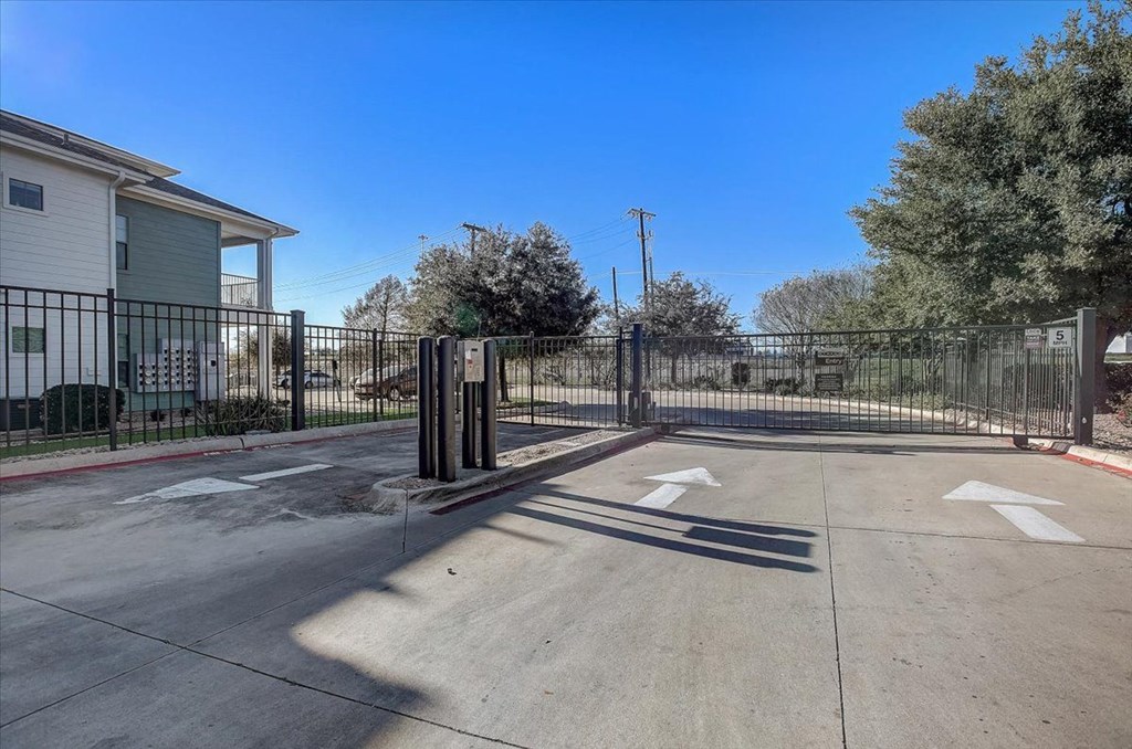 the entrance to a fenced in parking lot with a fence