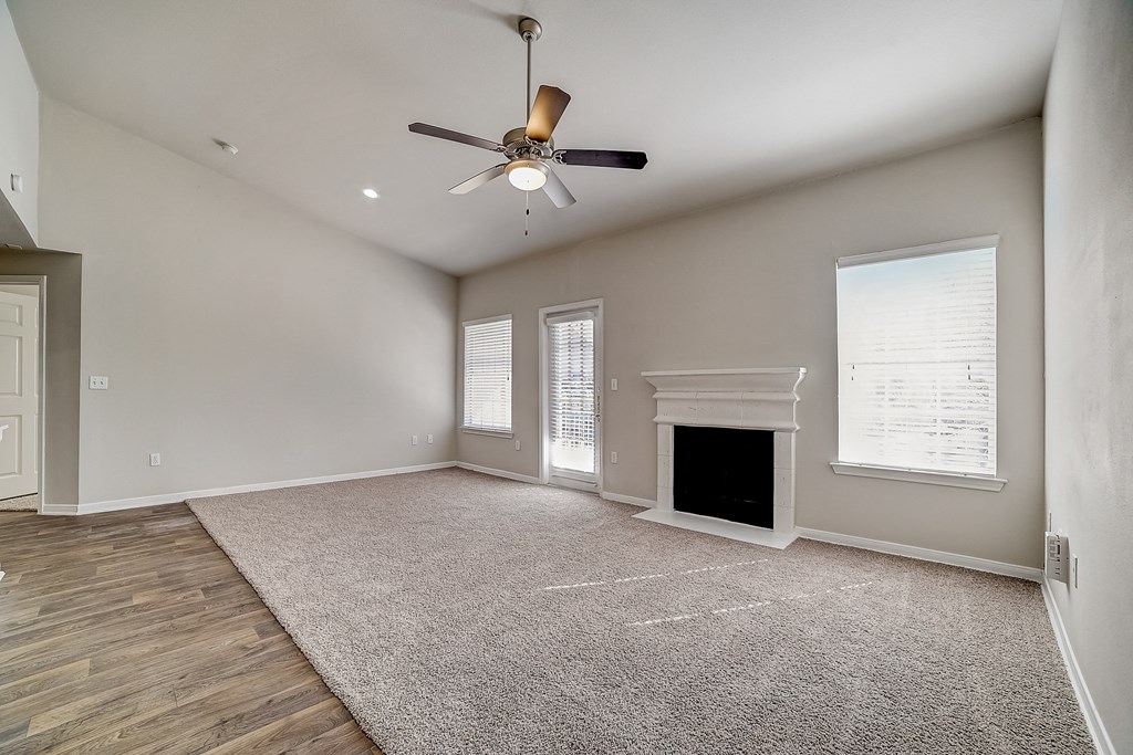 an empty living room with a ceiling fan and a fireplace