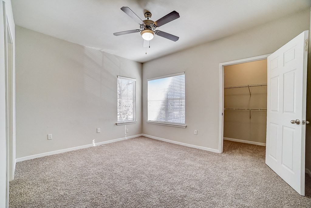 an empty room with a ceiling fan and a closet