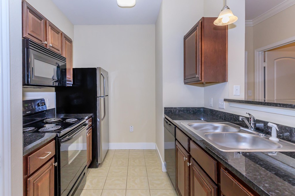 A kitchen with black appliances and brown cabinets.