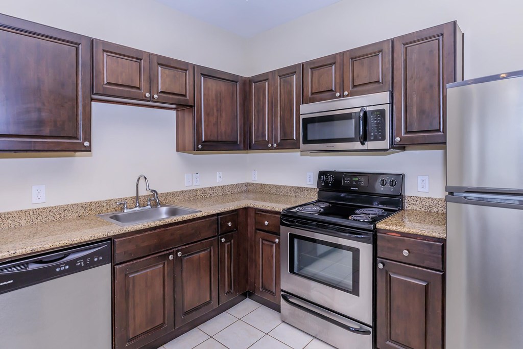 A kitchen with dark wood cabinets and stainless steel appliances.