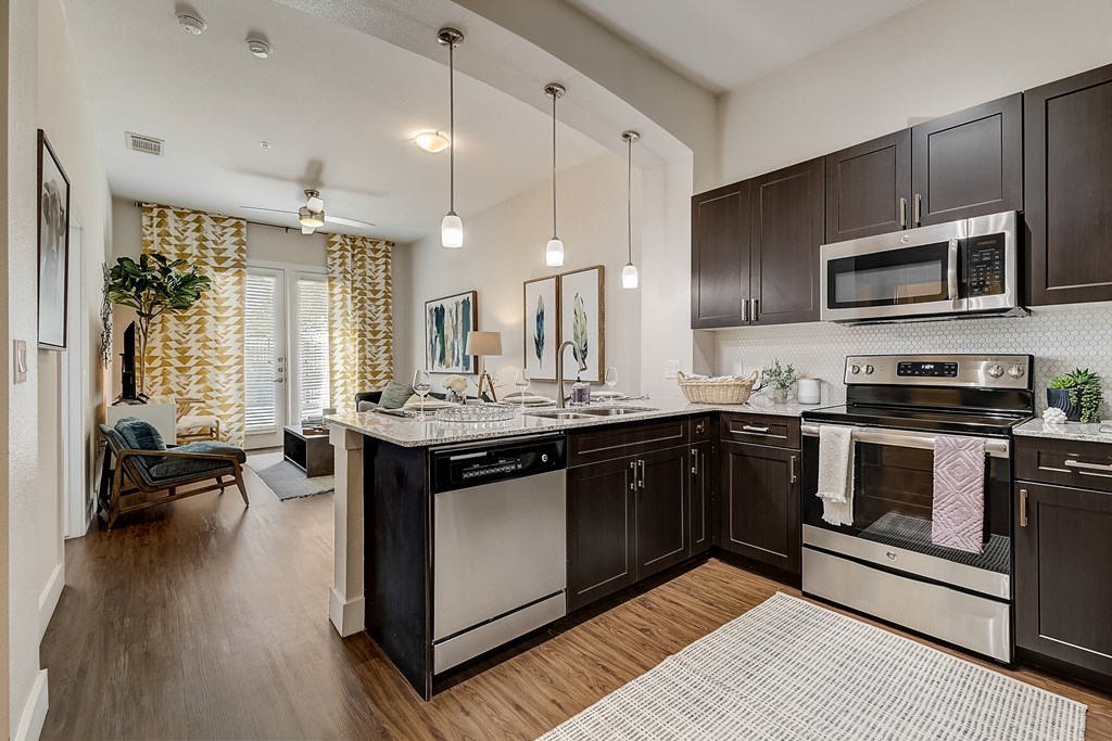 an open kitchen with stainless steel appliances and dark cabinets