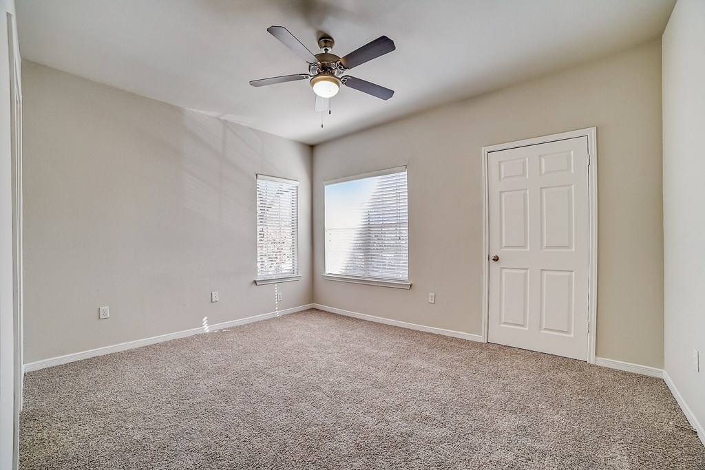 an empty living room with a ceiling fan and a window